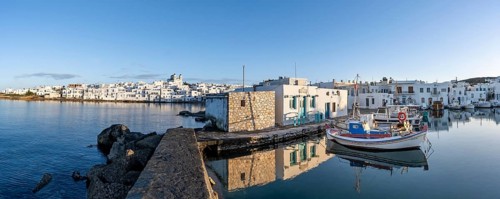 Panorama, view of the town of Naoussa and blue sea, harbour with fishing boats and reflection,