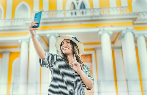 Young tourist woman with hat taking selfie in a square. Selfies and vacation concept. Beautiful