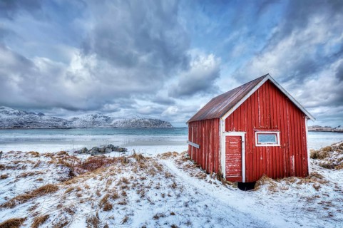 High Dynamic Range (HDR) image of red rorbu house shed on beach of fjord. Skagsanden beach, Lofoten