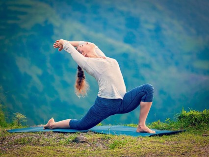 Yoga outdoors, sporty fit woman practices Hatha yoga asana Anjaneyasana, low crescent lunge pose