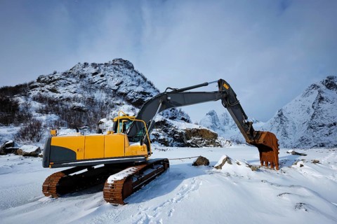 Old excavator with excavator bucket in winter. Road construction in snow. Lofoten islands, Norway,