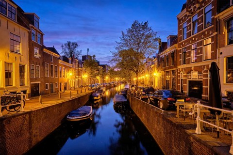 Typical Netherlands city view, canal with boats and houses illuminated in the evening. Haarlem,