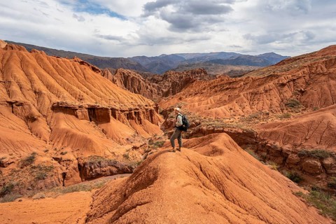 Mountaineer on a mountain ridge, view of eroded mountain landscape with sandstone cliffs, canyon