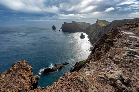 Red cliffs and rocks in the sea, coastal landscape with dramatic sky, Ponta de São Lourenço,