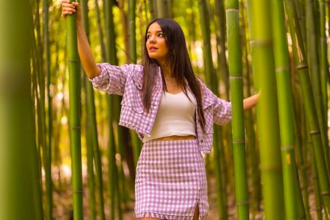 Young caucasian girl with a pink skirt in a bamboo forest. Enjoying the city on summer holidays in