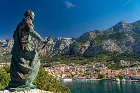Statue of St Peter in front of the city view of Makarska and the Biokovo Mountains, Croatia, Europe