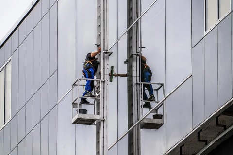 Window cleaner, facade cleaning, window cleaning, on a glass facade in Düsseldorf, ladder cage from