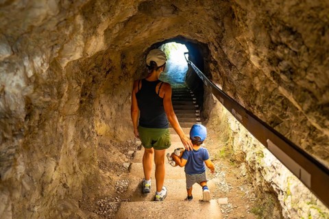 Mother and son walking up the stairs in a tunnel carved into the rock face at tolmin gorge in