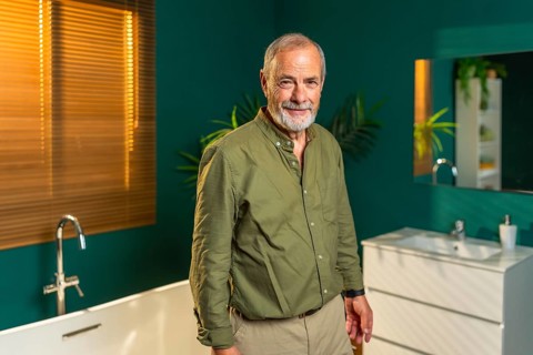 Portrait of a caucasian senior man standing in the bathroom at home smiling at camera