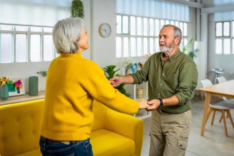 Happy hispanic senior couple dancing salsa in the living room
