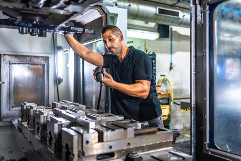 Serious male caucasian engineer inspecting a milling machine in an innovative metal cnc factory