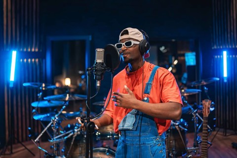 Young man singing into microphone, recording vocals for new album in professional music studio