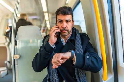 Frontal portrait of a serious caucasian adult, businessman using smartwatch while talking to the