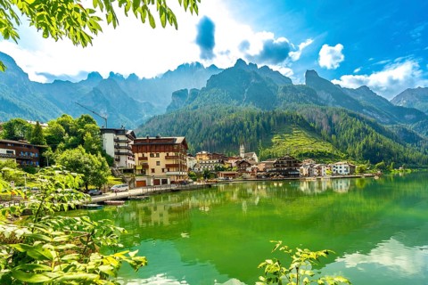 Stunning summer view of alleghe village reflecting on the emerald waters of lake alleghe,