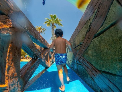 Child running through a water park during summer vacation in alicante, spain, enjoying the