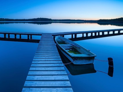 Wooden jetty with rowing boat at dusk, after sunset on Lake Schaalsee, Mecklenburg-Western