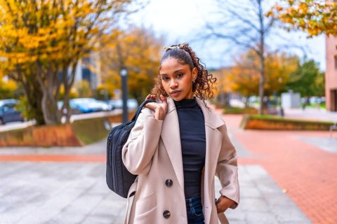 Young african american businesswoman carrying laptop bag walking along the city in autumn
