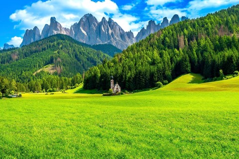 Green meadow with st. Magdalena church and stunning odle mountain range in dolomites, italy