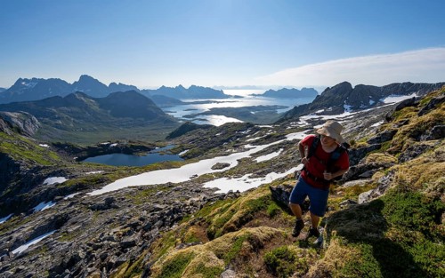 View of mountains and fjord landscape, mountaineers at the summit of Rundfjellet, Austenesfjord and