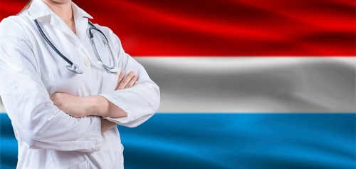 Doctor with crossed arms on Luxembourg flag. Luxembourg health and care concept. Female doctor on