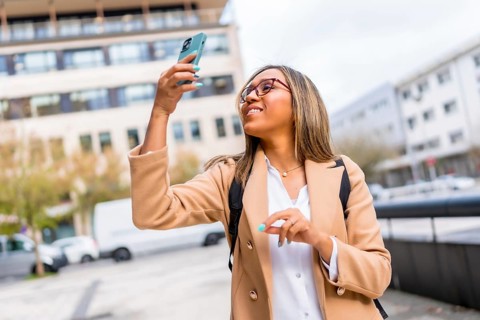 Dynamic shot of a happy latin woman walking along the city taking photos
