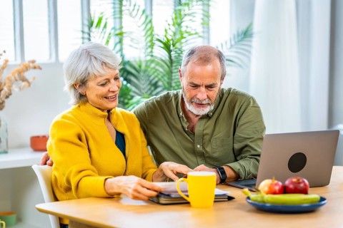 Relaxed senior couple doing paperwork and household accountability together using laptop and