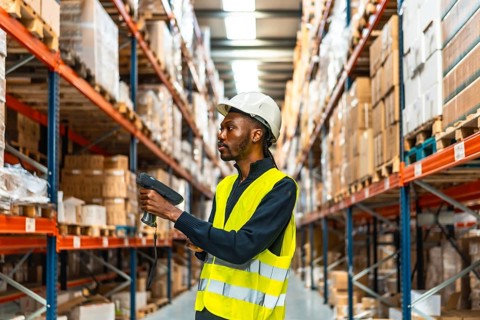 Side view of an african worker scanning packages with bar code reader