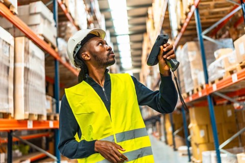 Frontal view of an african man scanning parcels in a distribution warehouse