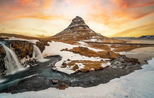 Beautiful sunrise on the famous Kirkjufell mountain next to the waterfall in winter in Iceland