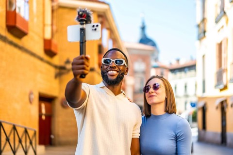 Multi-ethnic couple broadcasting with mobile phone and mic in the city