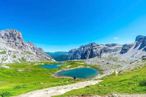 Breathtaking view of the tre cime di lavaredo and the surrounding lakes with a tourist enjoying the