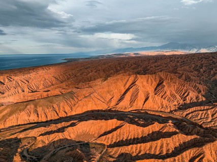 Landscape of eroded hills, badlands at sunset, Issyk Kul Lake in the background, aerial view,
