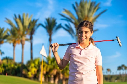 Horizontal close-up portrait of a girl with golf club on shoulder