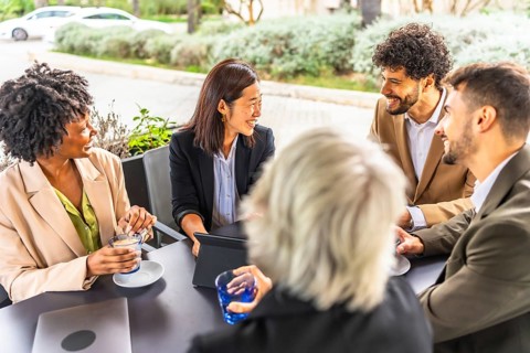 Multi-ethnic business people drinking coffee working with digital tablet sitting relaxed in a