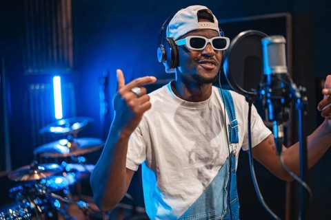 Talented african american artist wearing trendy sunglasses and headphones, passionately recording