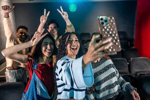Young people taking a selfie at the movie theater during a disco dance event, having fun and
