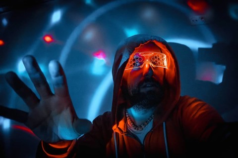 Bearded man with futuristic orange glasses interacting with holographic interface in virtual