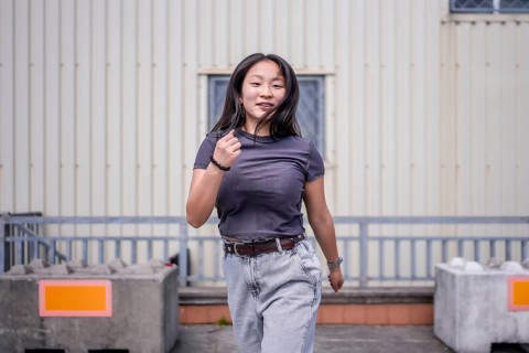 Passionate asian woman dancing k-pop choreography in the city next to an industrial building