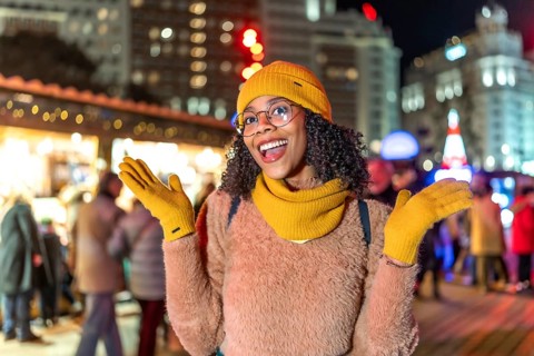 Young woman wearing yellow winter clothes expressing joy at christmas market in manezhnaya square,