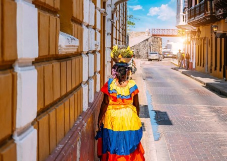 Colombia, lady in national colorful costume walking the streets of Walled City historic center of