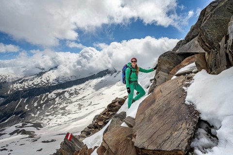 Mountaineer on a rocky hiking trail with snow, mountain panorama with snow-covered mountain peaks