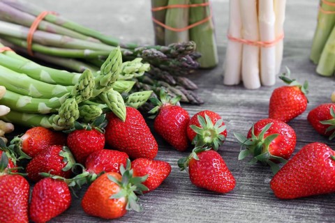 Green asparagus, white asparagus and fresh strawberries decorated on a rustic wooden table