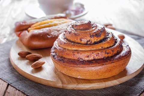 A cup of hot chocolate and buns on brown wooden background. close up