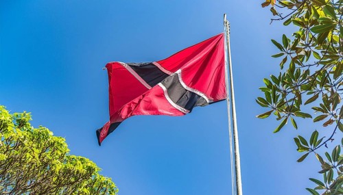 The flag of Tobago, Caribbean, flutters in the wind, isolated against a blue sky
