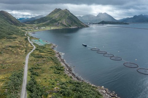 Aerial view of a salmon farm, rainy weather, grey sky, village Myre in the back, Vesteralen