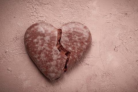 Glazed chocolate gingerbread, heart-shaped, top view, a broken heart, close-up, on beige