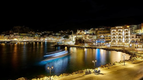 Harbour at night with illuminated buildings, lights reflected in the calm water, Pigadia, town and