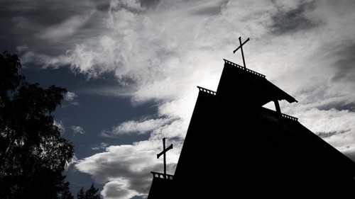 Silhouette of a church with two crosses against a dramatic cloudy sky, backdrop Kristin
