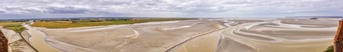 Expansive panorama with sand, watercourses and a wide horizon under a cloudy sky, Le