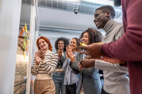 Side view of multi-ethnic group of colleagues applauding after a successful brainstorming process
